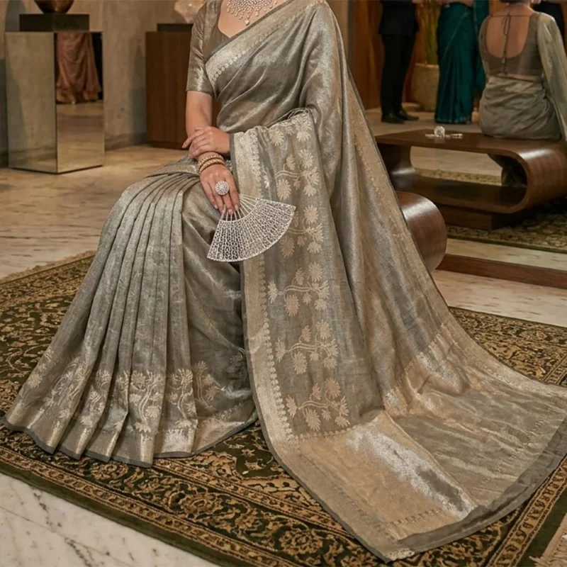 Model in a sitting pose wearing a Pistachio Green Banarasi silk tissue saree with a shimmering metallic finish and antique gold floral zari border