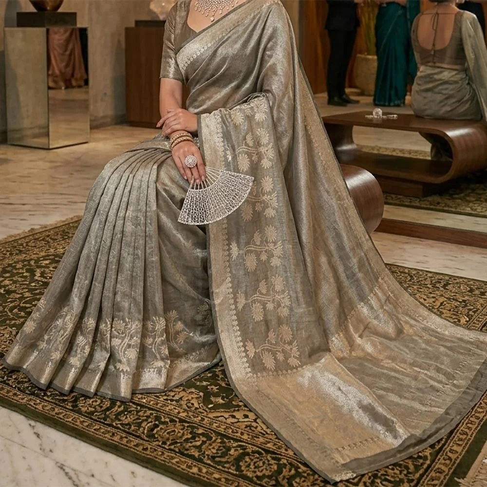 Model in a sitting pose wearing a Pistachio Green Banarasi silk tissue saree with a shimmering metallic finish and antique gold floral zari border